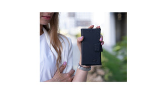 BlackBrook Carter Detachable Wallet Folio in Pebble Black, shown closed and held outdoors.