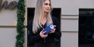 A picture of a woman holding an iPhone 17 Pro with a blue Blackbrook leather case.