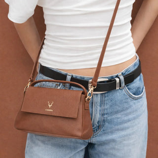 Person wearing a brown handbag with a visible brand logo against a brown background