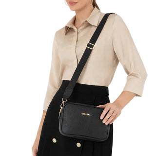 Woman holding a black handbag with a visible brand logo on a white background